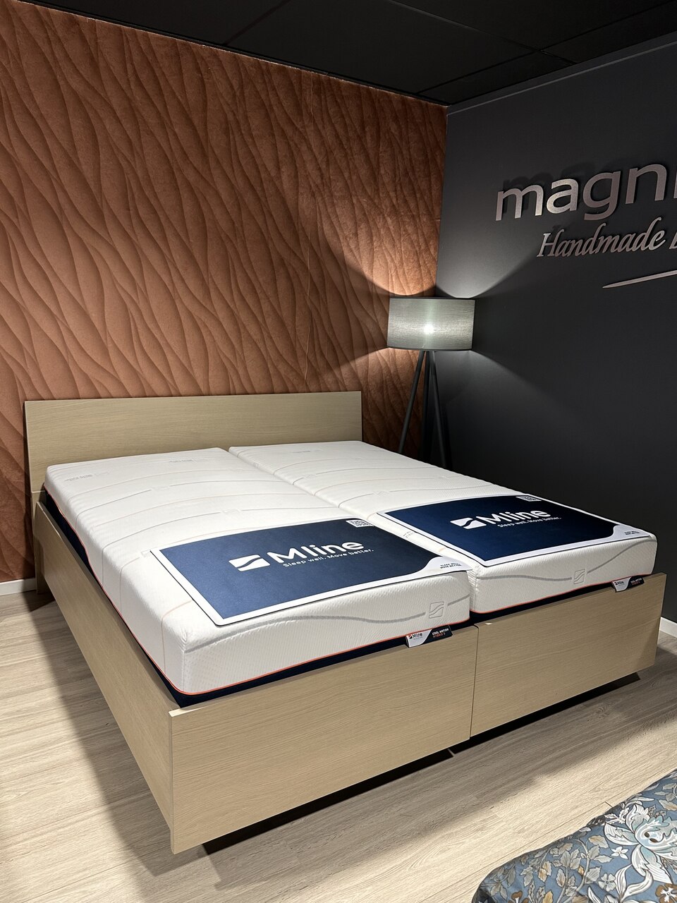 Showroommodel deelbaar ledikant 180x200 cm, eiken naturel fineer, met een achterwand voorzien van twee nachtkastjes met lades. Het bed heeft twee elektrisch verstelbare lattenbodems en hybride pocket matrassen met gel. Het onderstel is uitgerust met wielen voor een ruimtelijk en ‘zwevend’ effect.