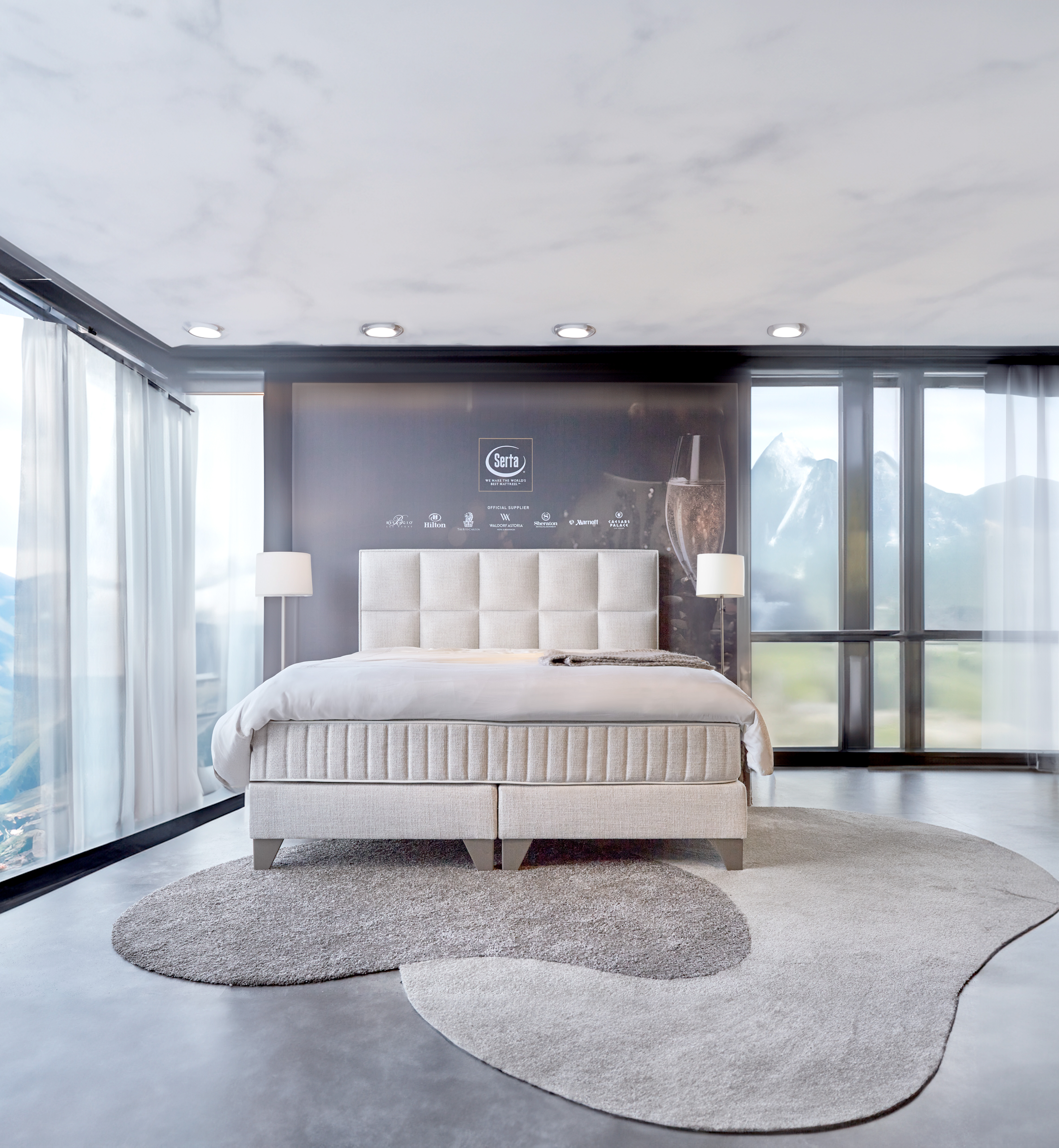 "Boxspring Hollywood van Serta in een luxe slaapkamer, inclusief een hoofdbord, champagnekleurige poten, splinternieuwe matrassen en een hoogwaardige gelfoam topper. Kleur: Oasis naturel."